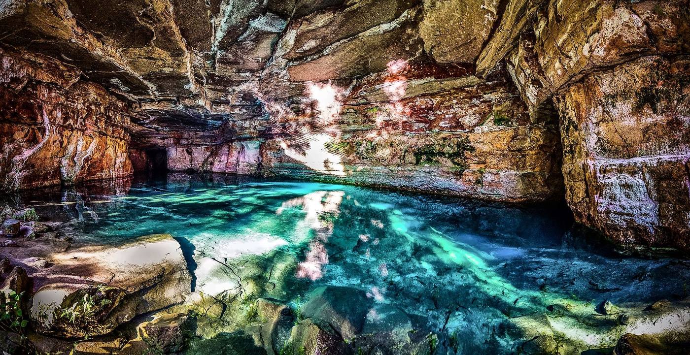 Lagoa de água azul-turquesa dentro de uma caverna de arenito