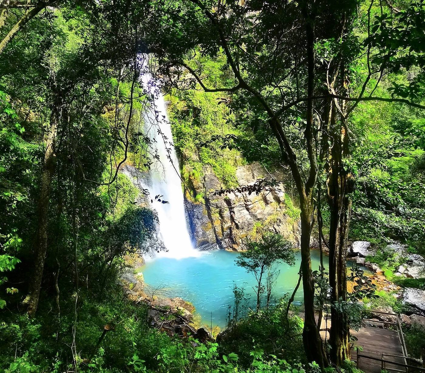 Cachoeira caindo numa piscina natural azul no meio da mata, em Bom Jardim