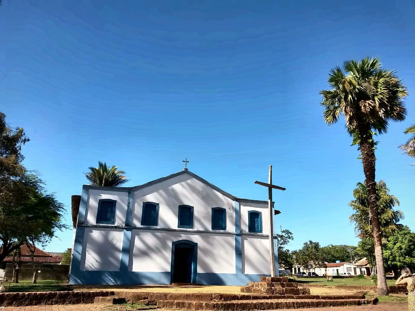 Igreja colonial branca e azul com palmeiras e céu azul