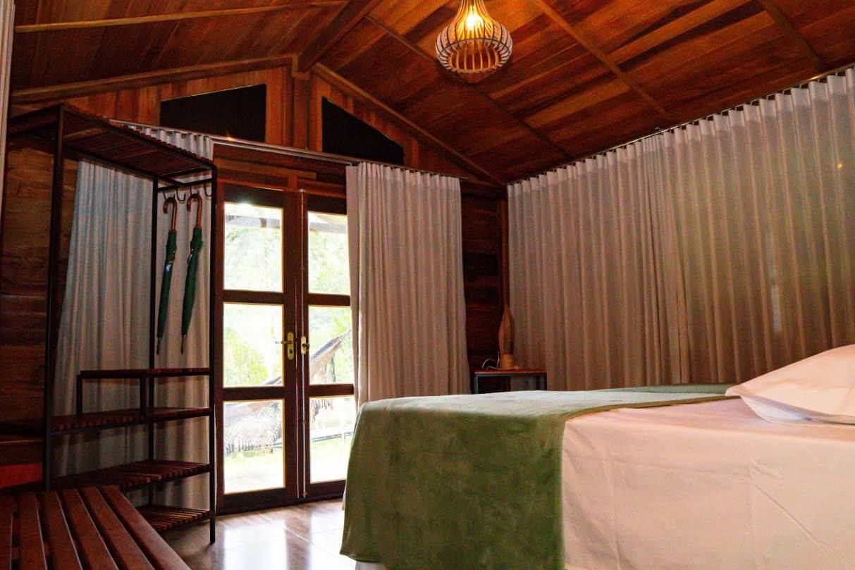 Suíte de chalé com cama de casal e vista para a mata